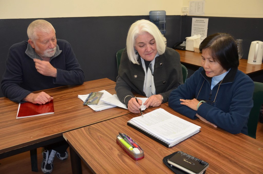 An asian woman learning a new skill from her tutors.