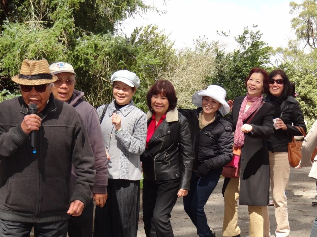 A social group of various ages and genders from multicultural backgrounds going for a walk in nature.